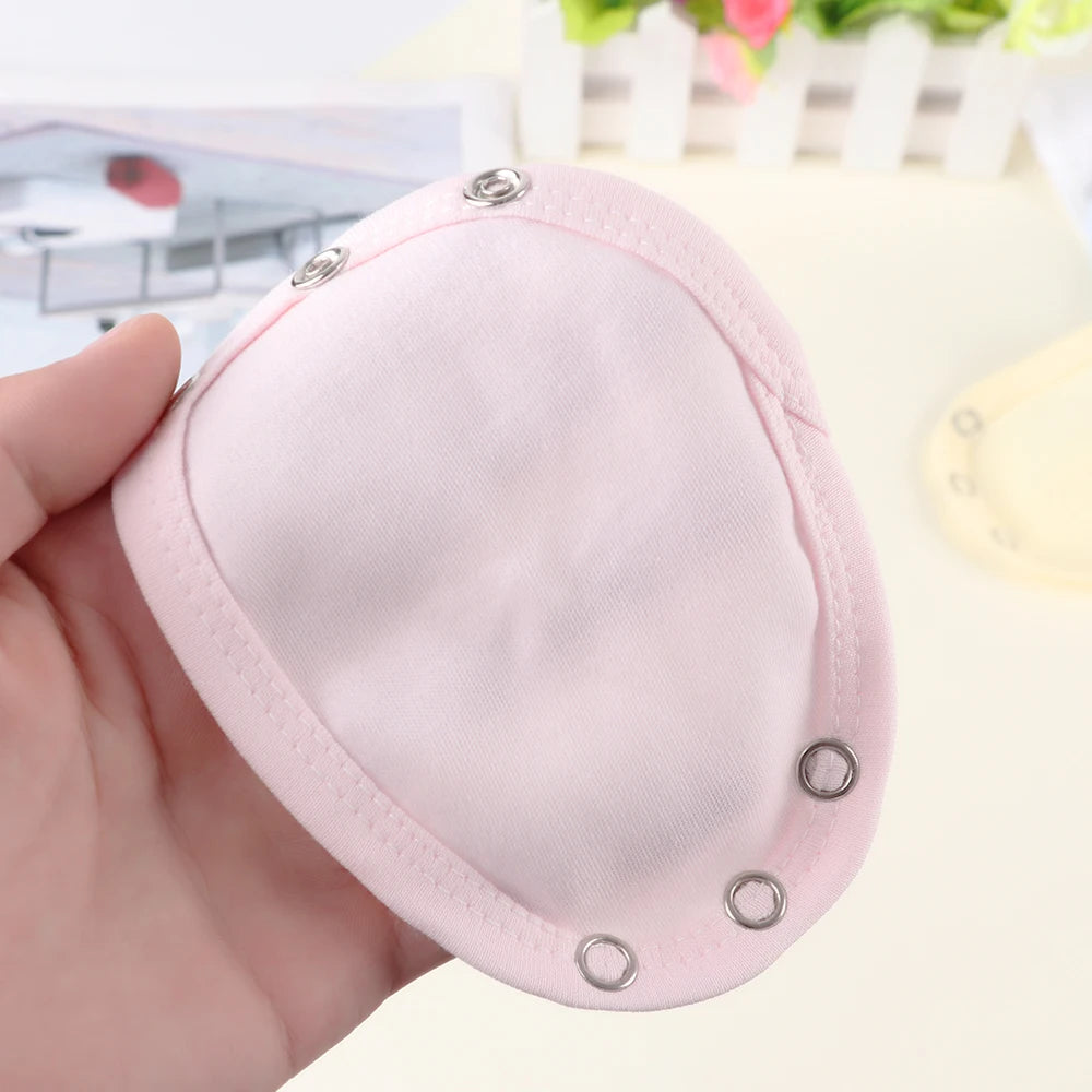 Une main tenant un petit porte-monnaie rose clair à bouton-pression conçu pour un bébé BABY-PREMA sur un fond flou avec des éléments floraux.
