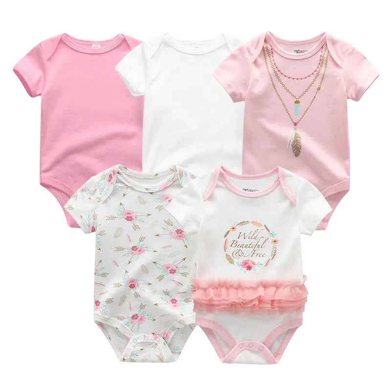 Un ensemble de cinq adorables vêtements pour bébé, comprenant le Lot 5 Bodys Coton | Imprimés Manches Courtes de BABY PREMA : trois unis (rose, blanc et rose avec motif colliers), un à motif floral et un blanc avec un tutu rose et un texte décoratif.