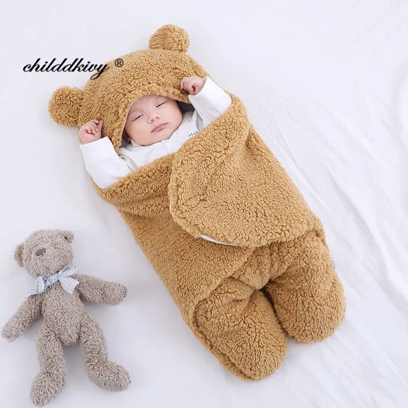 Un nouveau-né paisible dort confortablement dans une combinaison douillette en forme d'ours, avec tous les accessoires nécessaires pour bébé soigneusement organisés à proximité, et un adorable ours en peluche à ses côtés. La Couverture Doux Bébé 0-7 Mois de BABY-PREMA.