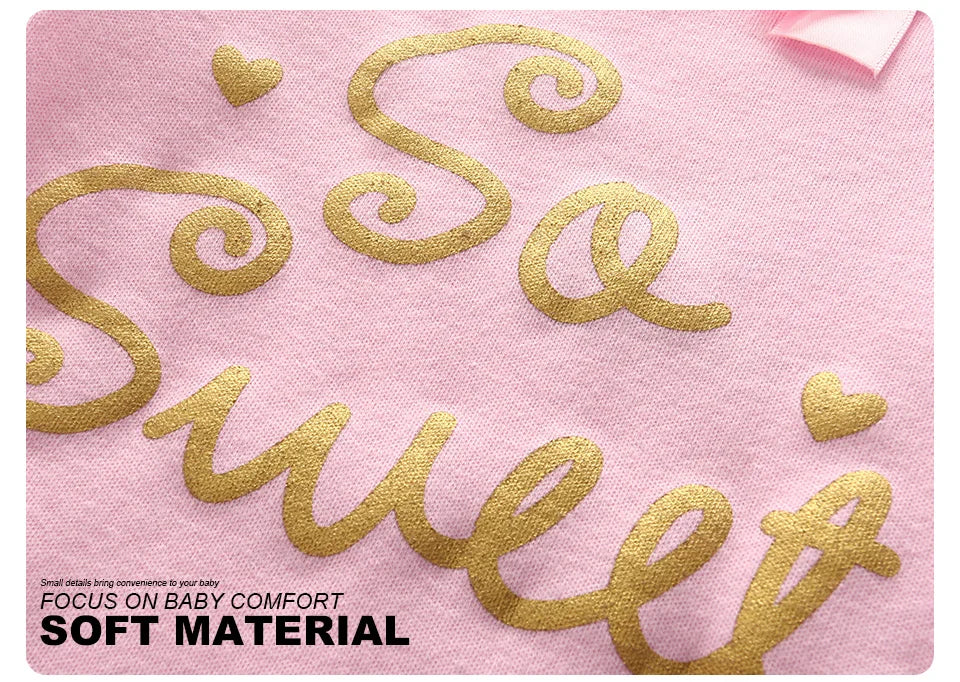 Gros plan d'un tissu rose avec un texte doré indiquant « So Sweet », orné de petits cœurs, et un texte en bas indiquant « FOCUS ON BABY CONFORT SOFT MATERIAL ». Parfaits pour les vêtements de bébé, ces Lot de 6 Pièces Body Coton Bébé de BABY PREMA assurent un maximum de confort à votre tout-petit.