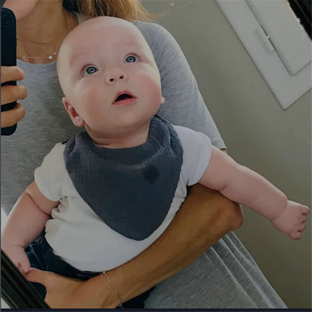 Un bébé aux yeux écarquillés et à l'air curieux, blotti dans les bras d'un parent parmi les douces serviettes BABY PREMA Bavoir 100% Coton pour Bébés, se reflète dans un miroir lors d'un instant selfie.