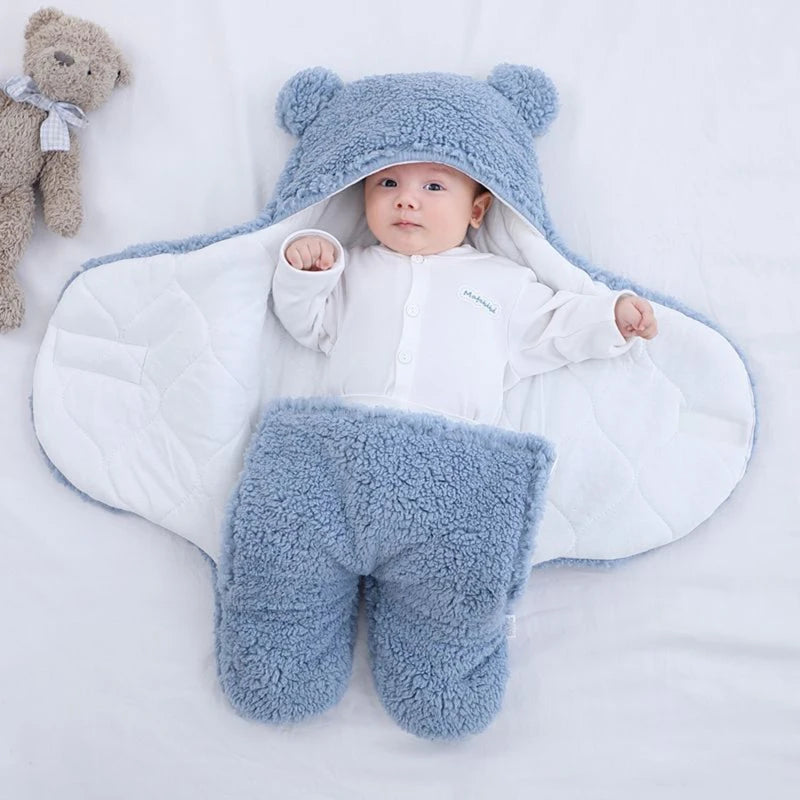 Un bébé bien au chaud, vêtu d'une tenue BABY-PREMA douillette sur le thème de l'ours, doté d'une capuche avec de petites oreilles, allongé sur une couverture douce, l'air curieux et content, entouré d'articles d'hygiène essentiels pour bébé.