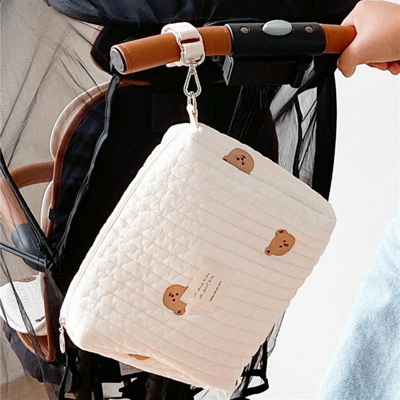 Sac à bandoulière blanc matelassé Sac de Couches Rangement Bébé orné de jolis ornements d'ours, suspendu avec désinvolture sur une poignée de scooter, donnant un ton tendance et ludique pour les déplacements urbains. Cette édition BABY PREMA "mon bébé" ajoute