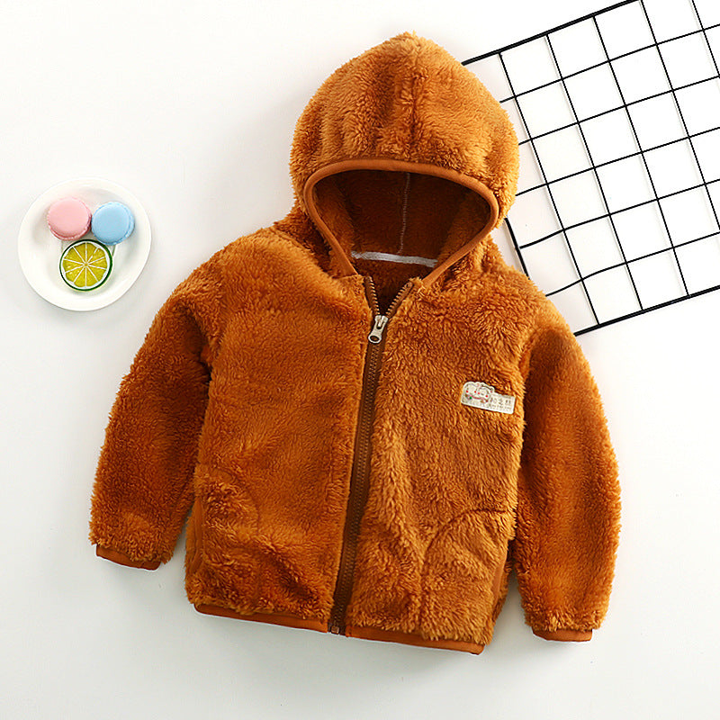 Manteau Gilet pour bébé orange brûlé pour tout-petit - Noukies avec une texture pelucheuse et un joli détail d'oreille d'ours sur la capuche, affiché sur une surface blanche et propre à côté d'une assiette décorative avec des macarons pastel et un BABY PREMA