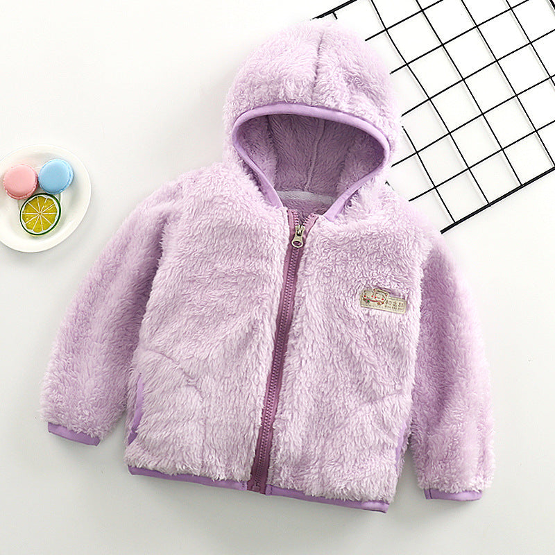 Manteau Gilet pour bébé violet douillet de BABY PREMA avec fermeture éclair sur fond blanc avec motif géométrique et accessoires jouets de couleur pastel.