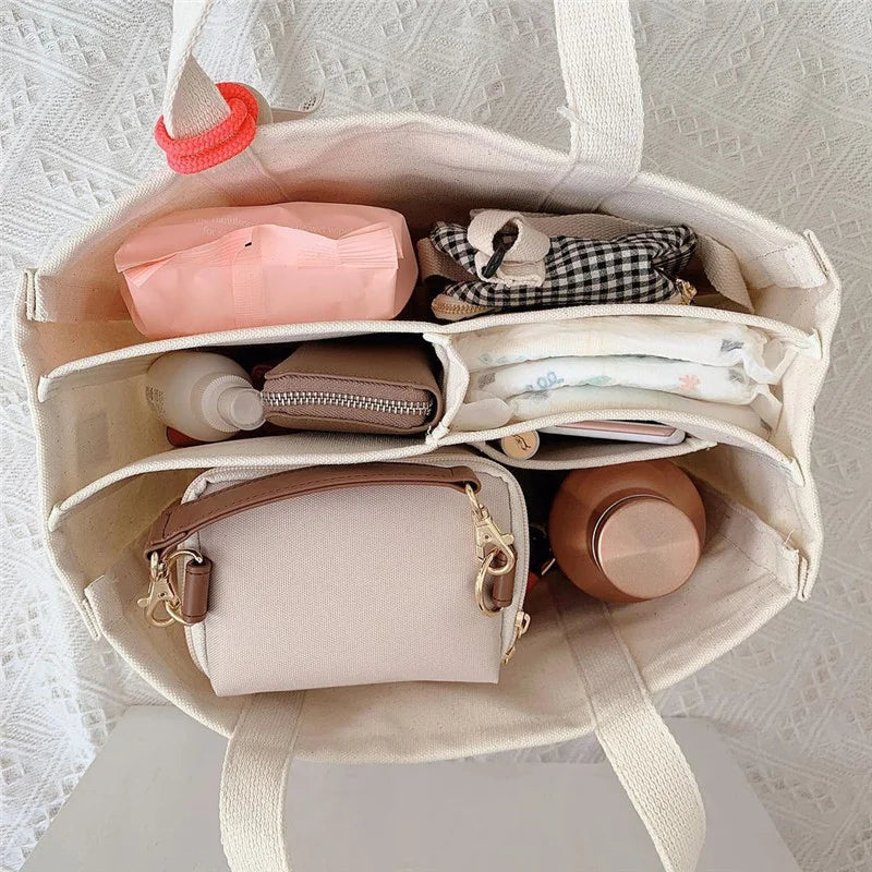 Un Sac à canapés pour bébé ouvert de BABY-PREMA soigneusement emballé avec des articles personnels de maternité, notamment un biberon rose, une pochette à motifs, une petite trousse, des articles de toilette et quelques autres essentiels, organisés pour un accès facile.