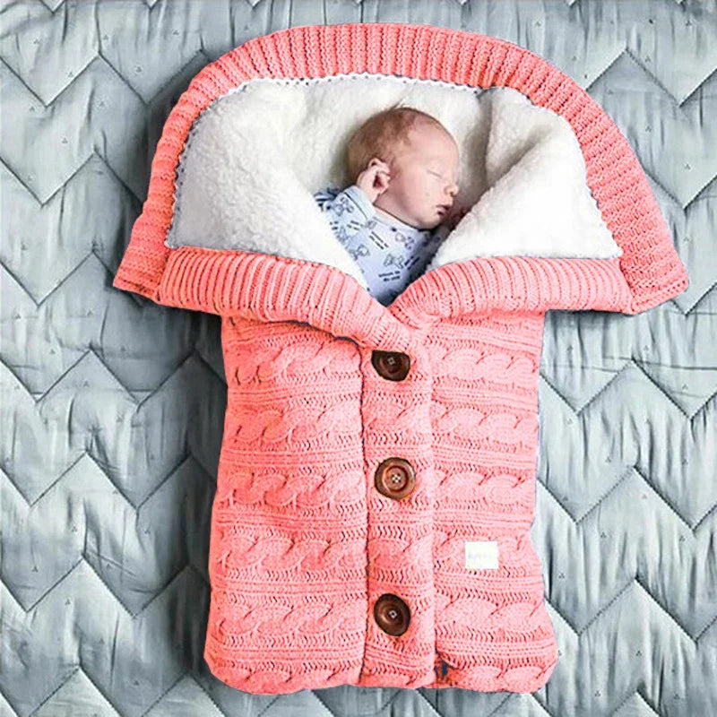Une paisible nouveau-né dort confortablement dans un accessoire bébé, une couverture de poussette pour bébé BABY PREMA, un sac de couchage tricoté douillet conçu comme une veste corail chaleureuse avec.