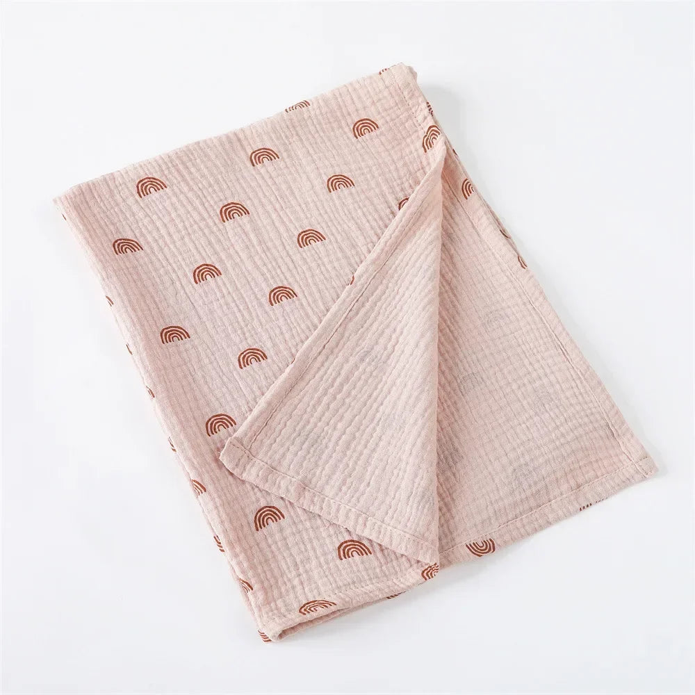 Tissu rose élégant avec une subtile texture gaufrée, conçu comme Couverture Emmaillotage en coton pour Bébé de BABY PREMA, et des motifs d'arches répétitifs, soigneusement pliés sur un fond uni.