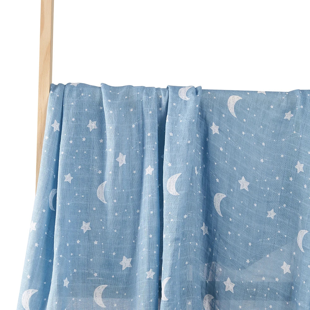 Tissu bleu à motif céleste d'étoiles et de croissants de lune conçu pour enfant dodo suspendu à une tige en bois sur fond blanc, Lange d'Emmaillotage Couverture de Baby Prema | 100% Cotton pour Bébé est le complément parfait à la décoration de votre chambre de bébé.