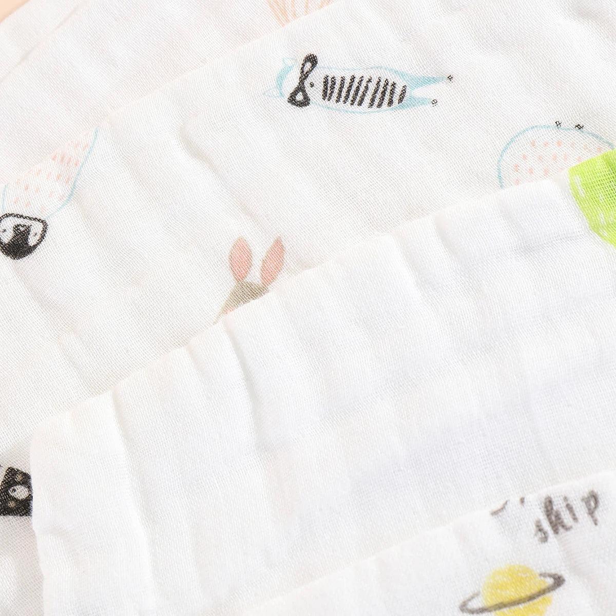 Gros plan d'un tissu blanc texturé conçu comme un Baby-Prema 5 Langes Coton Mousseline pour Bébé avec un joli motif d'illustrations enfantines colorées comprenant des poissons et un voilier.