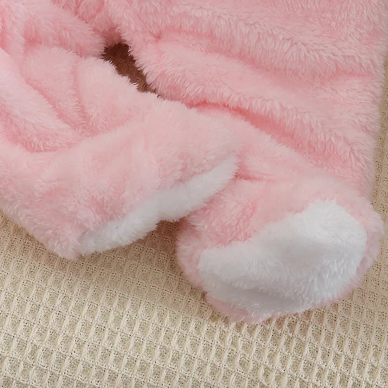 Image en gros plan d'un tissu rose moelleux aux textures douces, faisant probablement partie d'un produit textile tel que la BABY-PREMA Combinaison à Capuche | Manches Longues, présentées sur un fond beige tissé pour un confort haut de gamme.