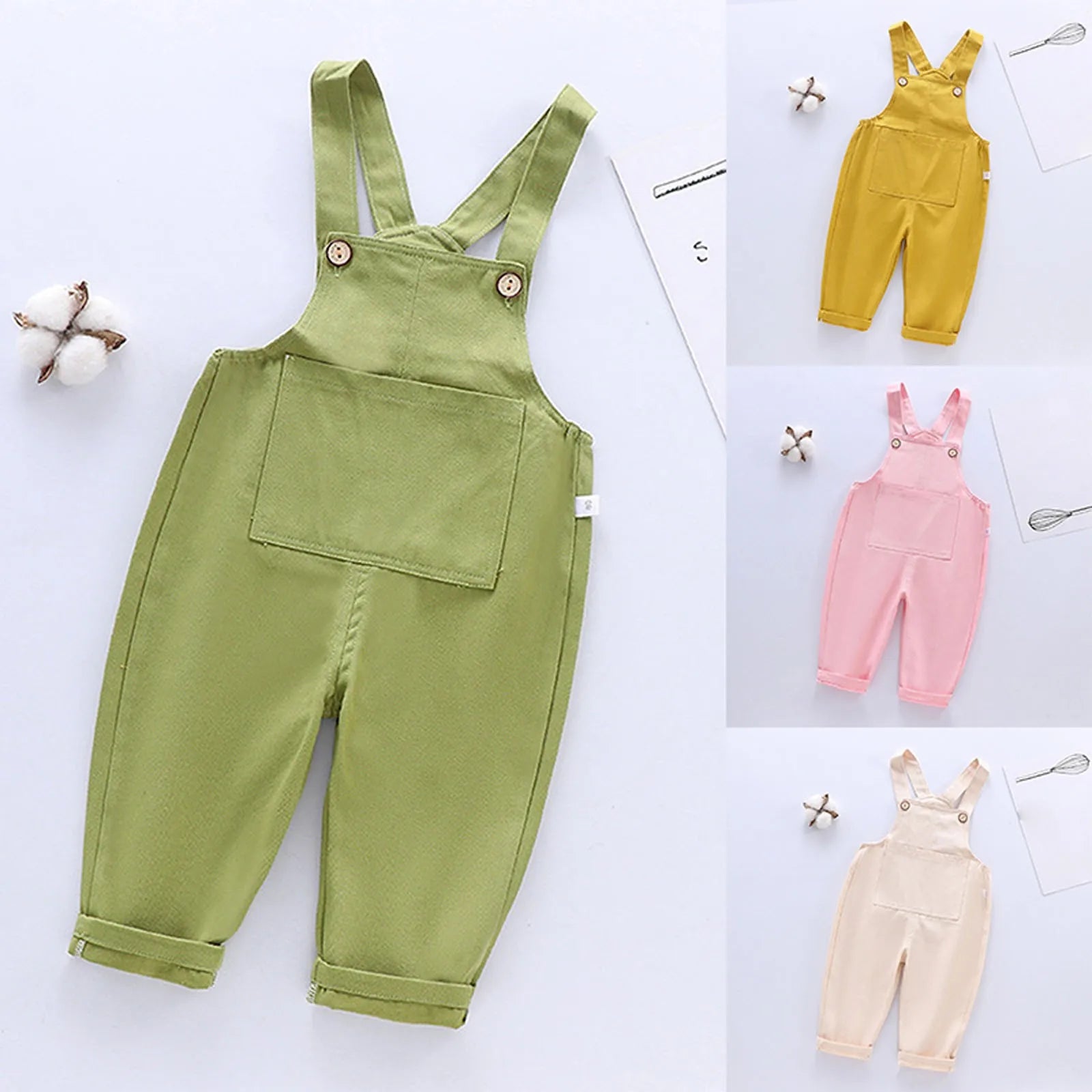 Quatre salopettes pour bébé aux couleurs vert, jaune, rose et crème sont exposées. La Salopette Bébé Unie verte de BABY-PREMA est mise en évidence, dotée d'une poche avant et de bretelles boutonnées. Un cotonnier est également visible pour mettre en valeur la matière naturelle de ces jolis articles vêtement enfant.