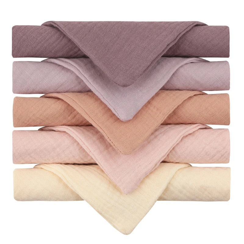 Une sélection soigneusement empilée de luxueux foulards Lot de 5 Langes Bébé en Coton dans un dégradé de couleurs chaudes allant du beige clair au mauve foncé, parfait pour un enfant de BABY PREMA.