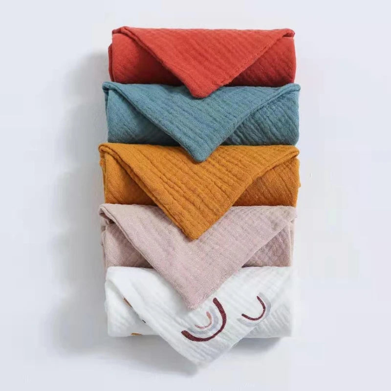 Un assortiment soigneusement empilé de serviettes Lot de 5 Langes Bébé en Coton conçues pour la peau délicate d'un bébé prématuré sur fond uni. (Nom de marque : BÉBÉ PREMA)