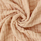 Accessoires bébé en Couvertures Mousseline BABY PREMA gracieusement tordue en spirale, mettant en valeur sa texture délicate et ses plis doux.