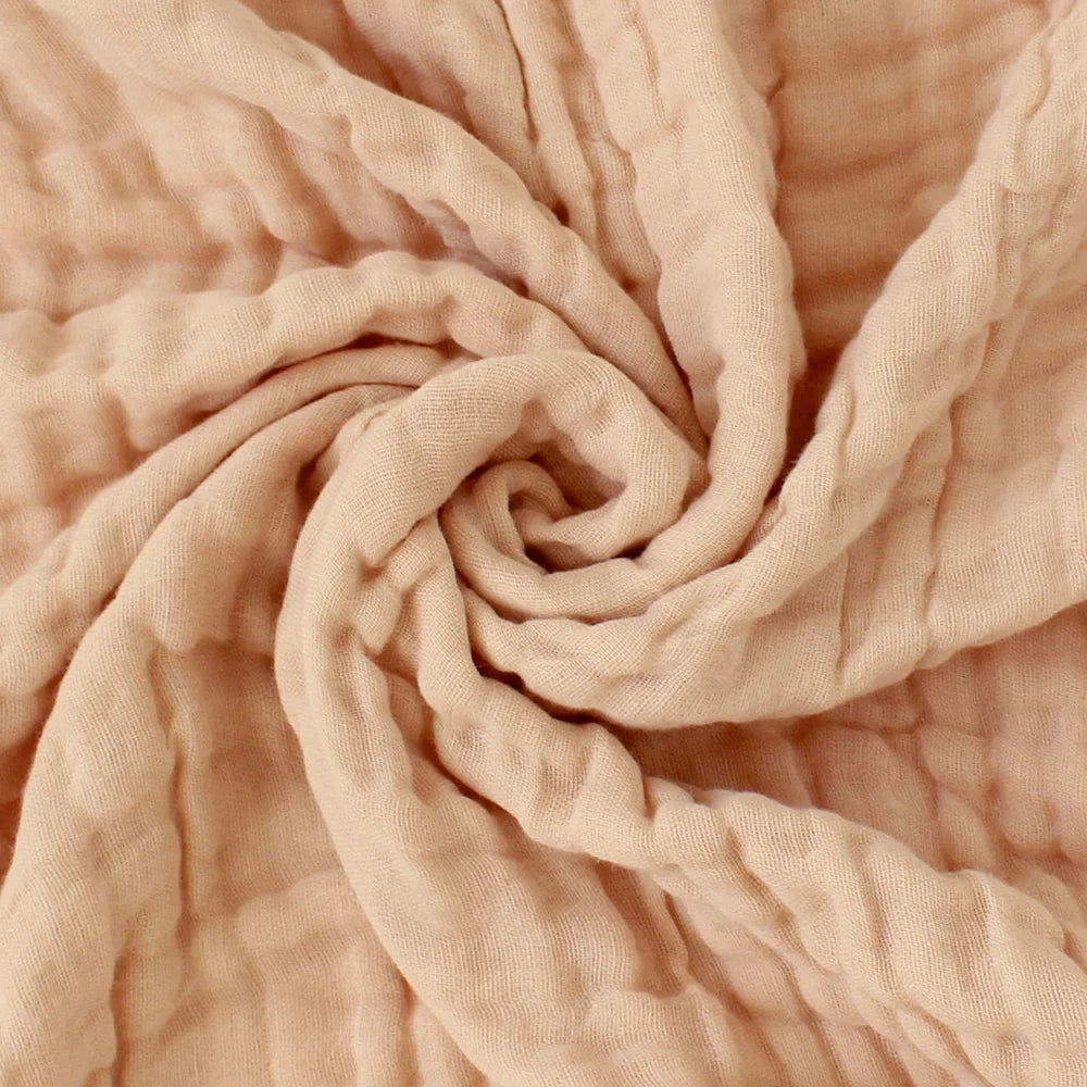 Accessoires bébé en Couvertures Mousseline BABY PREMA gracieusement tordue en spirale, mettant en valeur sa texture délicate et ses plis doux.