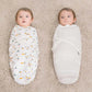 Deux adorables bébés bien emmaillotés dans des couvertures, allongés côte à côte et regardant vers le haut avec des yeux curieux, entourés de leur jolie BABY PREMA Couverture Bébé Cocoon 100% Coton.