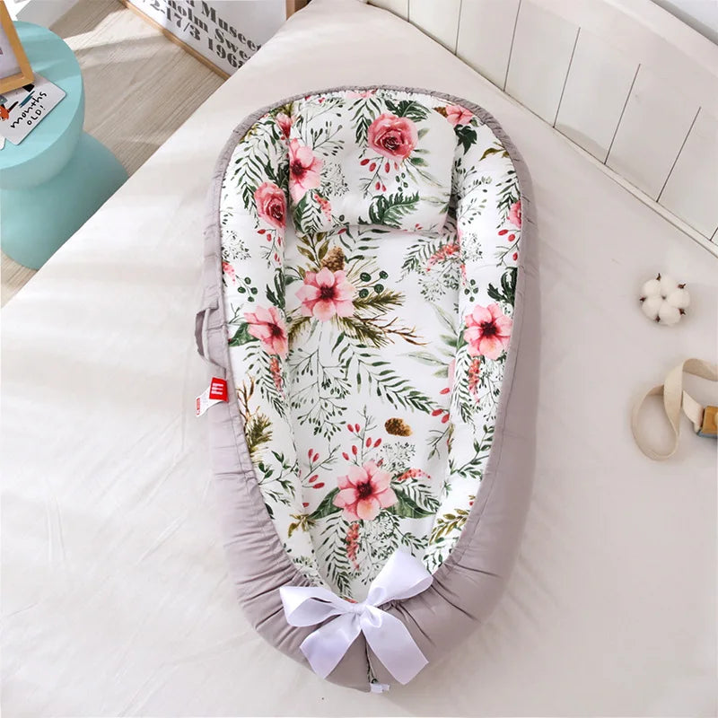 Nid de bébé avec motif floral et bordure grise, présentant un design doux et confortable pour le confort et la sécurité du bébé. Ce Lit de Bébé Portable léger de BABY-PREMA assure une facilité de transport tout en gardant votre enfant en sécurité.