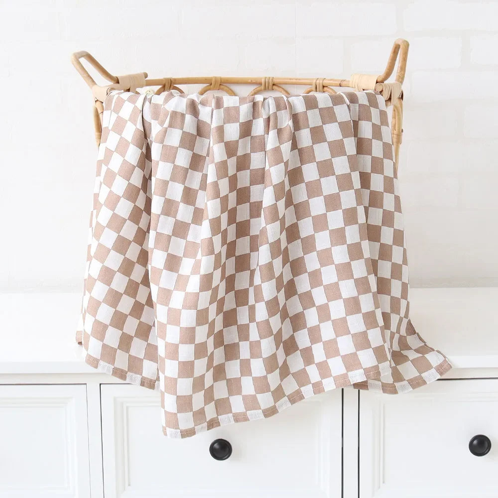 Un tissu à carreaux beige et blanc drapé sur un panier en osier contenant les articles nécessaires pour bébé, dans une cuisine lumineuse.
Nom du produit: BABY PREMA Couvertures en Bambou Bébé | Emmaillotage