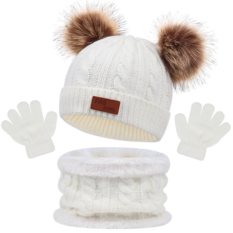 Un Ensemble 3Pièces Bonnet Gants pour Bébé de BABY PREMA, comprenant un bonnet tricoté blanc avec des pompons moelleux, une écharpe tricotée blanche assortie et une paire de gants blancs.