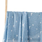 Tissu bleu à motifs lunes et étoiles blanches, idéal pour la Couverture Lange d'Emmaillotage BABY PREMA | 100% Coton pour Bébé, drapé sur un poteau en bois sur fond clair.