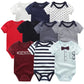 Un Pack de 5 Bodies Coton Doux Bébé de BABY PREMA dans différentes couleurs et motifs, dont des rayures, des étoiles, des couleurs unies et un texte « #GENIUS » ; parfait comme cadeau de naissance.