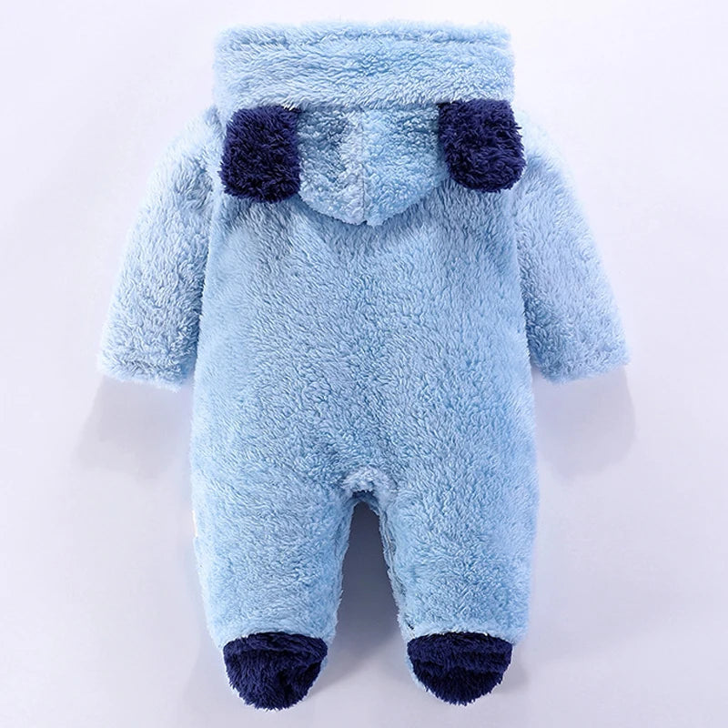 A Fluffy BABY-PREMA Combinaison à Capuche | Manches Longues affichées sur un fond blanc, principalement de couleur bleu clair avec des accents bleu foncé sur la capuche, les poignets et les pieds. La capuche comporte deux poches saillantes bleu foncé ressemblant à des yeux.