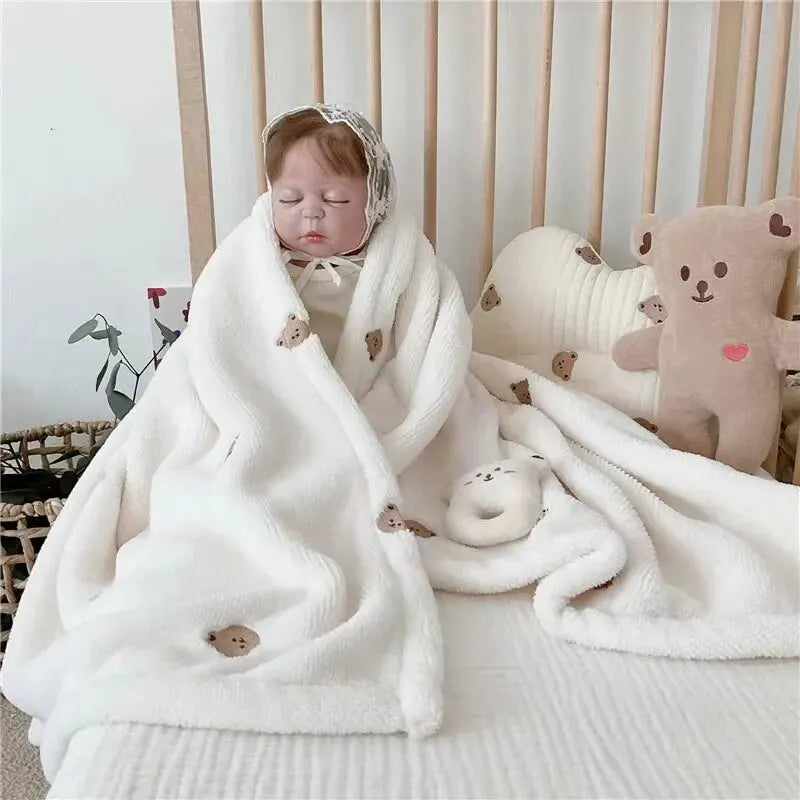 Un moment paisible : un bébé endormi enveloppé dans une couverture Couverture de Bébé en Molleton de Corail de BABY PREMA, accessoires bébé à ses côtés, créant une atmosphère sereine et cosy.