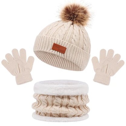 Un ensemble d'accessoires d'hiver coordonné comprenant un BABY PREMA Ensemble 3Pièces Bonnet Gants pour Bébé, comprenant un bonnet tricoté beige avec un pompon en fausse fourrure, une paire de gants beiges légers et un cache-cou assorti.