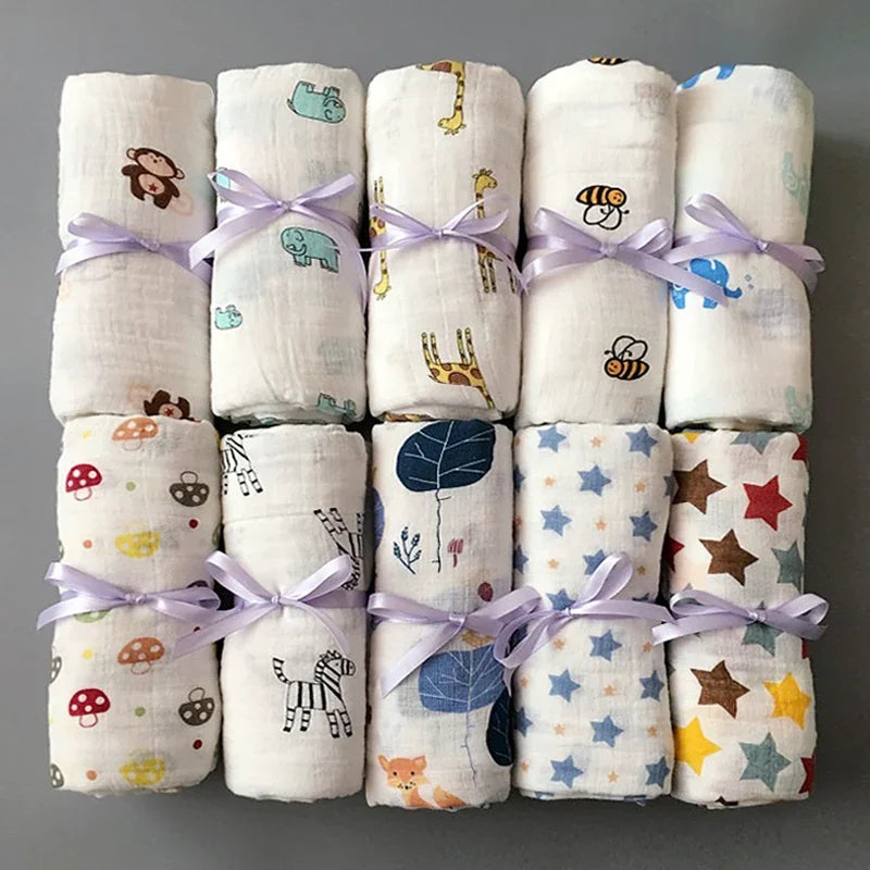 Une collection colorée de langes en mousseline en coton pour bébé prématuré BABY PREMA, liés avec un ruban et présentant divers motifs ludiques.