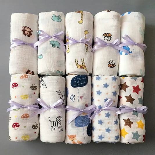 Une collection colorée de langes en mousseline en coton pour bébé prématuré BABY PREMA, liés avec un ruban et présentant divers motifs ludiques.
