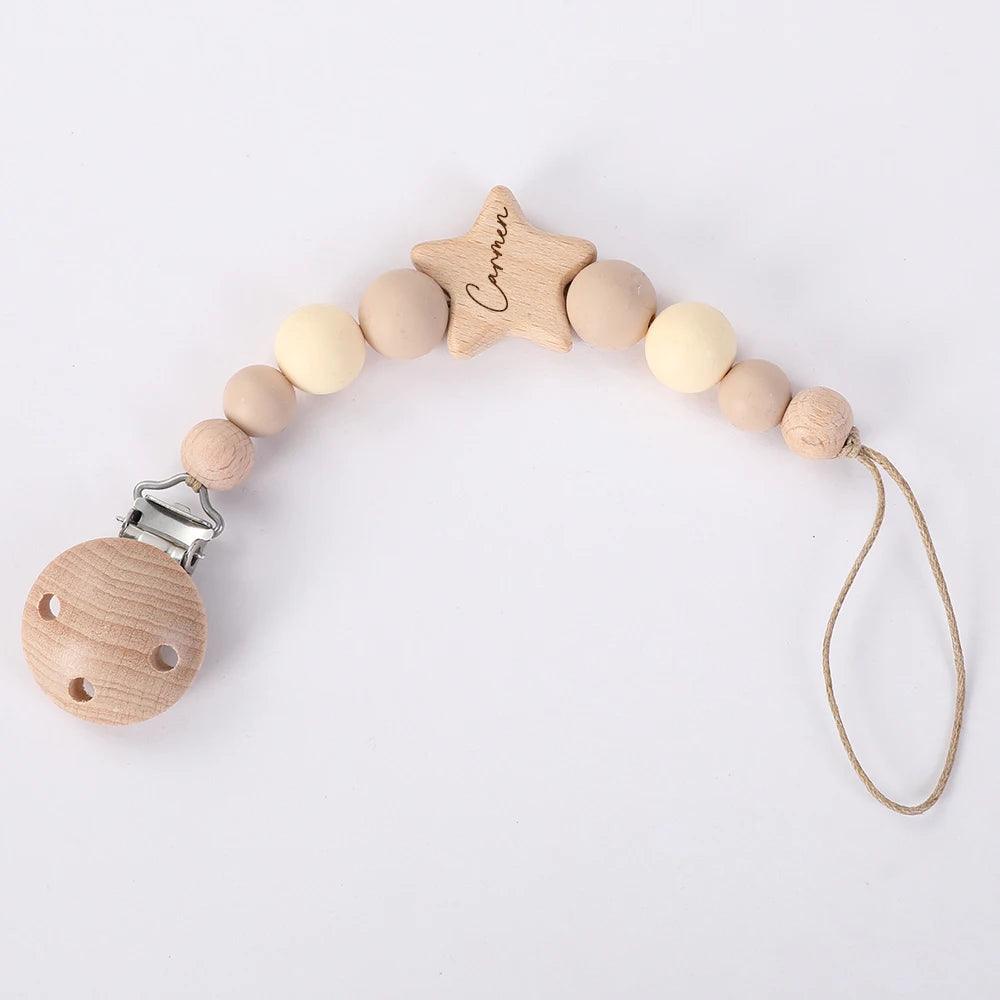 Accessoire bébé : Attache Sucette Bébé Personnalisé de BABY-PREMA avec perle en forme d'étoile personnalisable et perles rondes naturelles sur fond blanc.