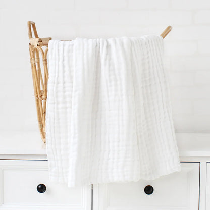 Une serviette blanche moelleuse suspendue au-dessus d'un porte-serviettes en bois dans une salle de bain lumineuse et propre, conçue pour un BABY PREMA Lange Bébé | Couverture Emmaillotage Mousseline.