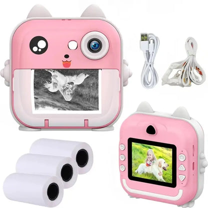 Un appareil photo instantané rose et blanc avec un charmant motif de chat, parfait comme Appareil photo Polaroid | Pour Enfants Mini. La vue avant présente une photo imprimée tandis que l'écran arrière, trois rouleaux de papier, un câble USB et un câble de chargement soulignent sa praticité pour capturer des souvenirs avec impression instantanée. Marque : BÉBÉ PREMA.