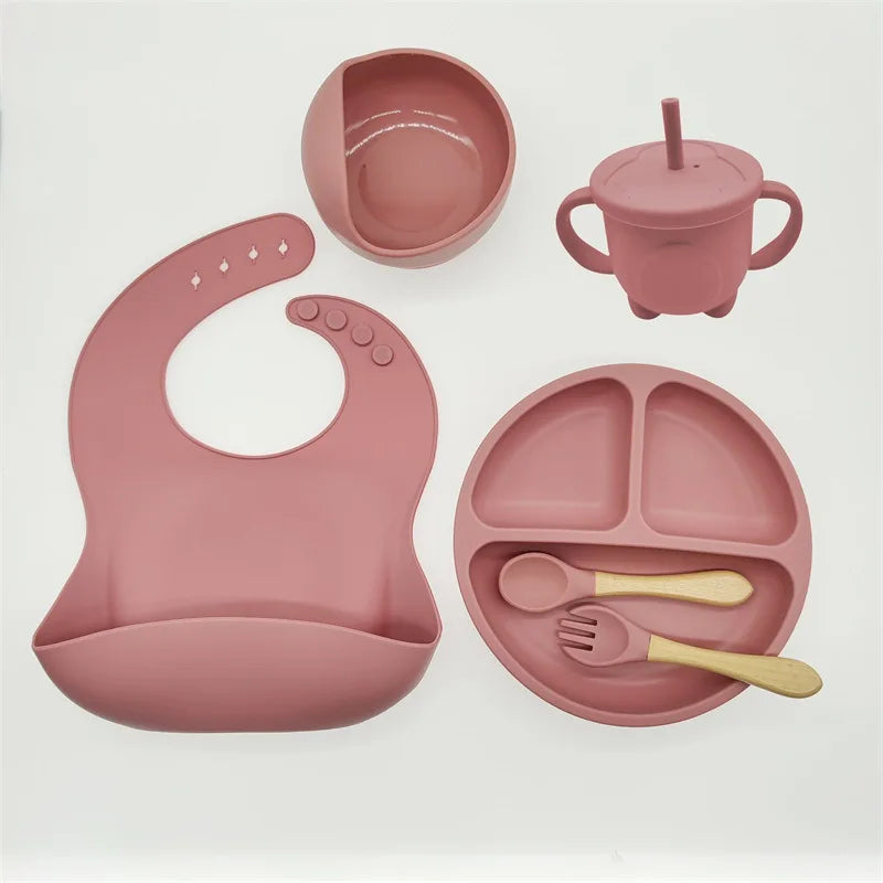 L'Ensemble 6-8 Pièces de Vaisselle pour enfants de BABY PREMA en silicone de haute qualité comprend un bavoir, une assiette sectionnée, des bols à ventouse, un bol, une tasse en paille, une cuillère et une fourchette, le tout placé sur un fond blanc.