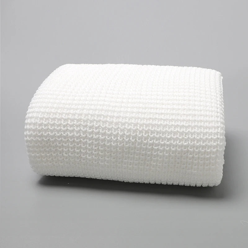 Une Couverture Bébé Tricot Fin 90*70cm pliée à texture gaufrée blanche - Couverture Baby-Prema de Baby-Prema est gracieusement affichée sur une surface grise unie.