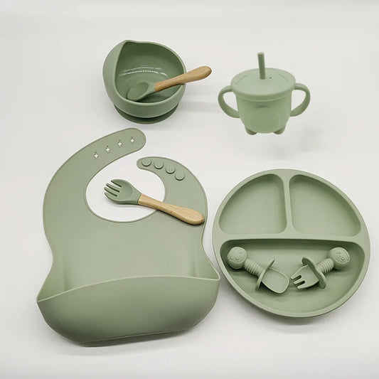 Un ensemble d'articles d'alimentation pour bébé en silicone vert de haute qualité comprenant un bavoir, des cuillères, un bol, un gobelet avec poignées et de la vaisselle pour enfants comme une assiette divisée avec ventouses, Ensemble 6-8 Pièces de Vaisselle pour enfants par BABY PREMA .