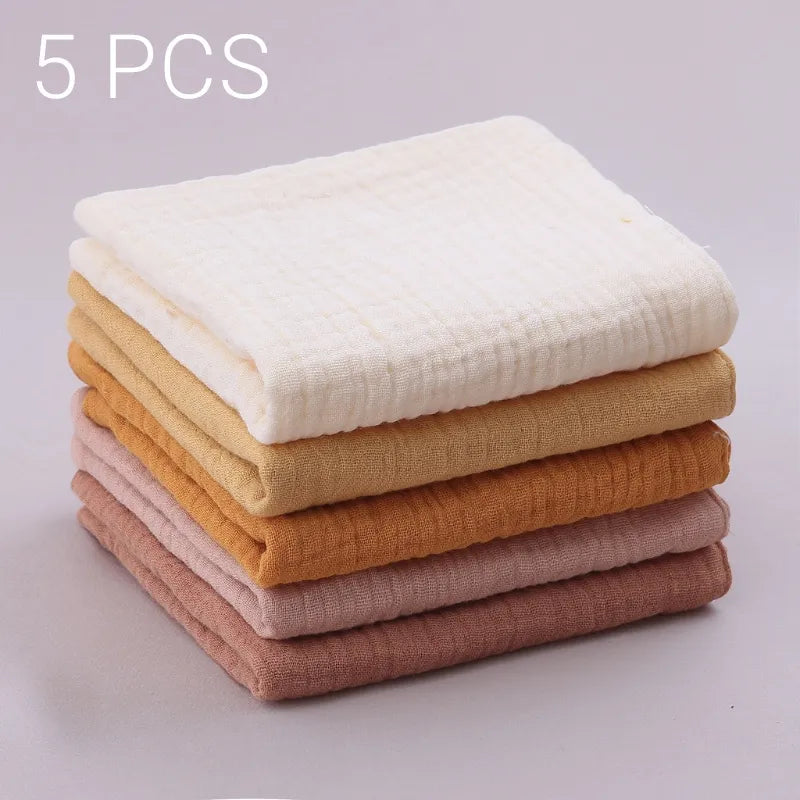 Une pile de cinq serviettes pliées dans différentes nuances allant du blanc au marron clair, étiquetées comme un ensemble de 5 pièces Lot de 5 Langes Bébé en Coton par BABY PREMA.