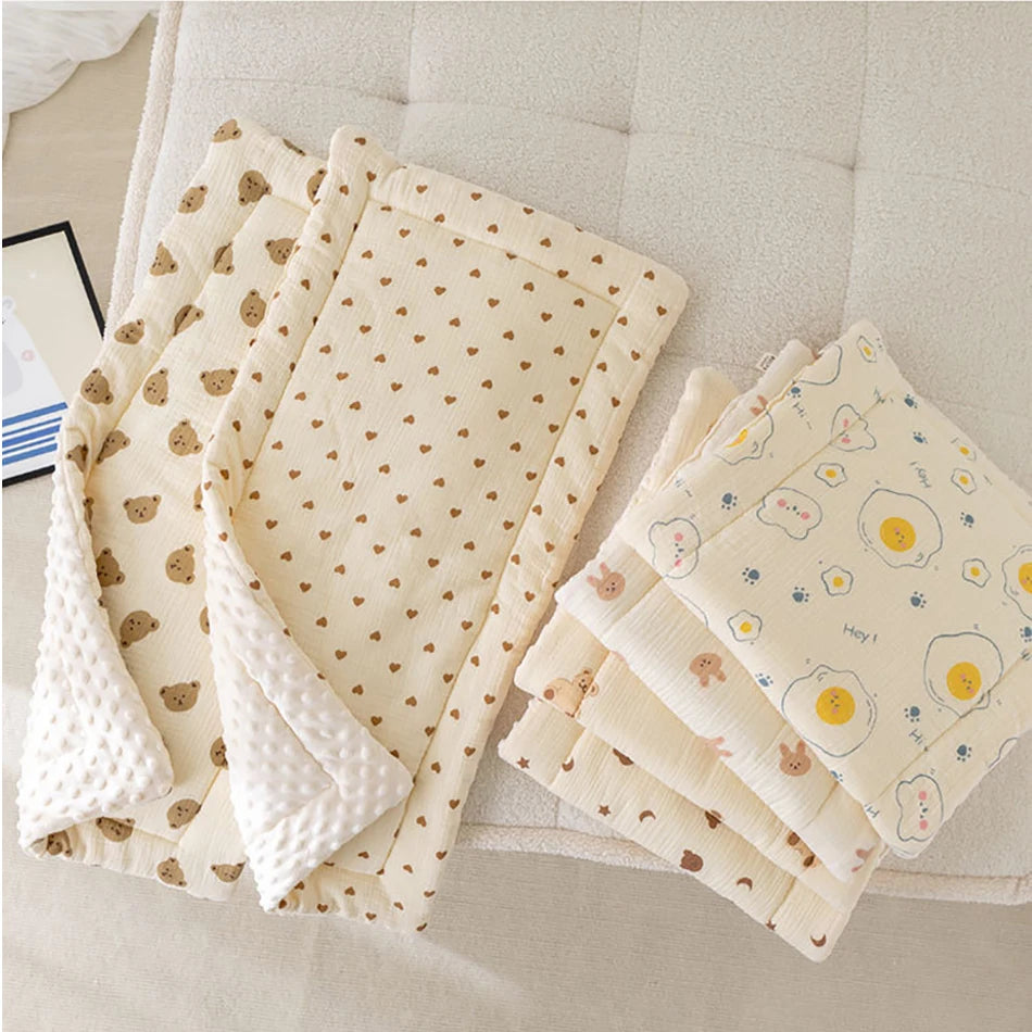 Une collection de couvertures Coussin de Siège de poussette pour Bébé douces et douillettes avec de jolis motifs disposés sur un canapé confortable, évoquant une sensation de chaleur et les soins nécessaires pour bébé par BABY PREMA.