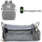 Un sac à langer Baby Prema polyvalent avec port USB qui se transforme en berceau de voyage avec fonction de chargement, présenté sans moustiquaires.