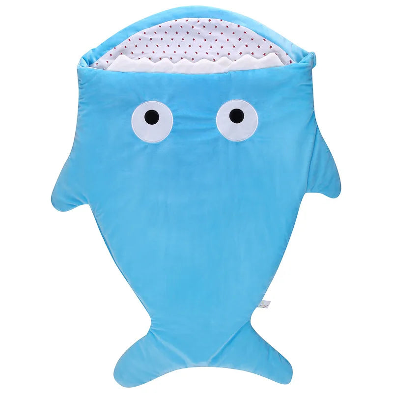Une jolie gigoteuse bébé requin de style dessin animé en bleu avec une doublure à pois blancs et de grands yeux sympathiques sur la capuche, parfaite comme couverture en polaire Ultra Doux et Moelleux accessoire bébé BABY PREMA.