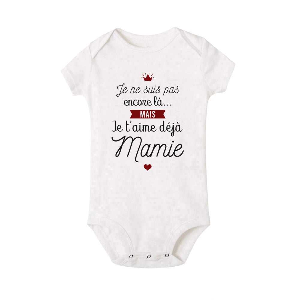 Un Body Coton été Imprimé blanc de BABY-PREMA avec un texte en français qui dit "Je ne suis pas encore là... MAIS Je t'aime déjà Mamie." Il comporte un petit cœur rouge et un graphique de couronne rouge, ce qui en fait le cadeau grand-mère parfait pour votre enfant en bas âge.