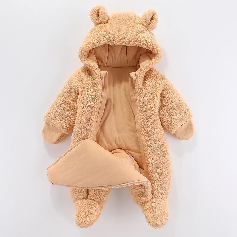 Une Barboteuse Chaude à Capuche beige en peluche de BABY-PREMA avec une capuche ornée de jolies oreilles d'ours, affichée sur un fond blanc uni. la combinaison est ouverte pour montrer la doublure intérieure.