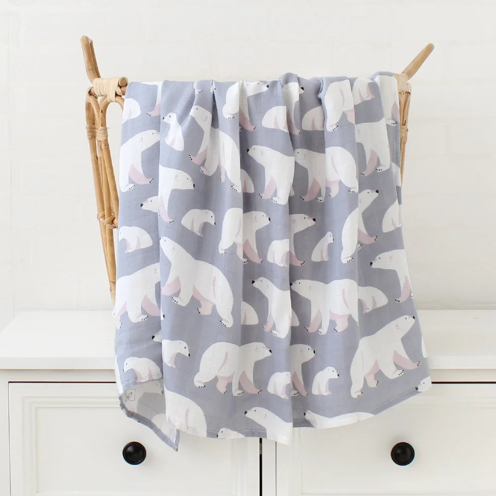 Une couverture Lange Bébé en Bambou & Coton douce et grise avec un motif d'ours polaire blanc répété drapé sur une échelle en bois sur un fond blanc par BABY PREMA.