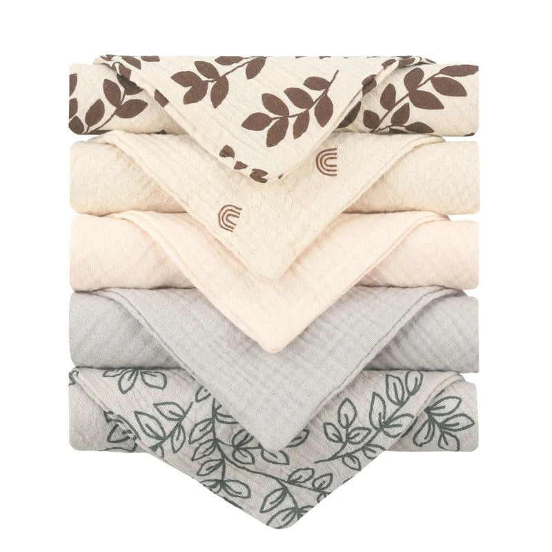 Une pile de serviettes pliées soigneusement disposées avec des motifs variés dans des tons terreux, toutes fabriquées à partir du tissu Lot de 5 Langes Bébé en Coton de BABY PREMA.