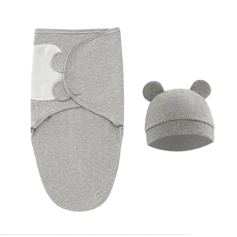 Un ensemble d'emmaillotage gris et de bonnet assorti avec de jolis détails d'oreilles, présentés sur fond blanc, articles essentiels Couverture Bébé Cocoon 100% Coton de BABY PREMA.