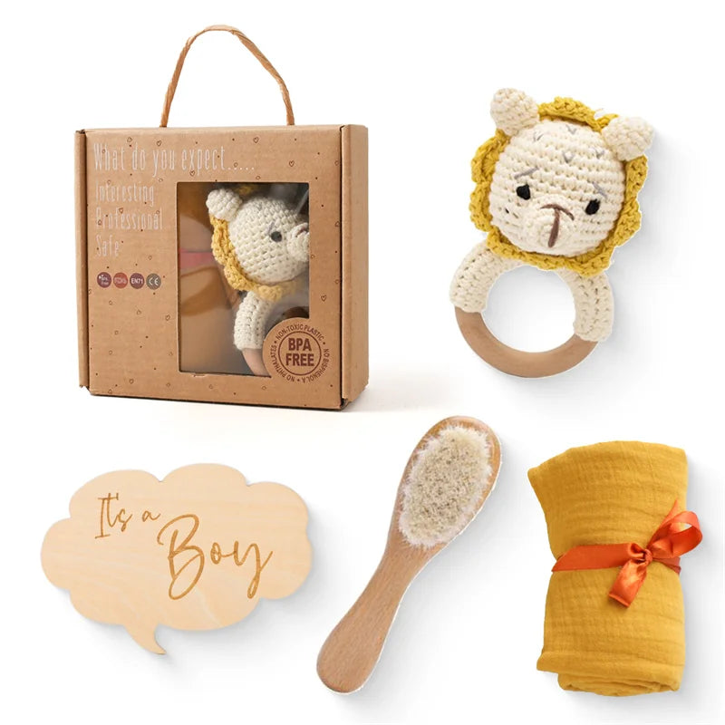 Un charmant coffret cadeau Coffret Cadeau Naissance Bébé sur le thème "c'est un garçon", composé d'un hochet animal au crochet, d'une brosse en bois pour l'hygiène de bébé, d'un torchon jaune et du BABY PREMA.