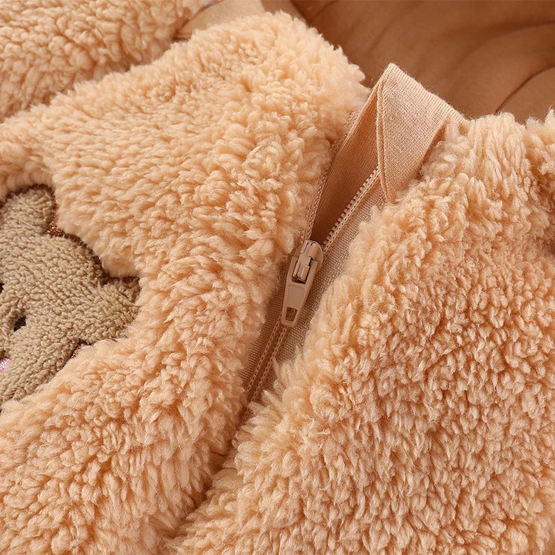 Gros plan d'un ours en peluche avec une fermeture éclair beige partiellement ouverte, révélant un tissu texturé et doux qui crée une apparence douillette idéale pour BABY-PREMA Barboteuse à Capuche | Combinaison Épaisse Bébé.