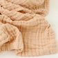 Tissu Couvertures Mousseline doux couleur pêche à la texture froissée, disposé en plis doux, parfait comme nécessaire pour bébé de BABY PREMA.