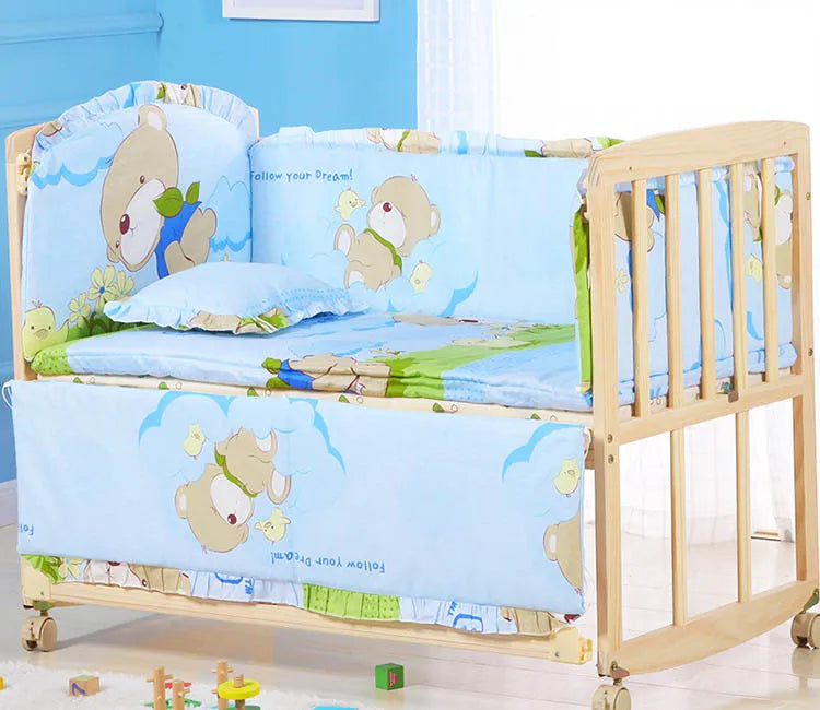 Une chambre d'enfant joyeuse comprenant un berceau en bois BABY PREMA avec une literie bleue ornée d'illustrations d'ours de dessins animés, encourageant à « suivre vos rêves ! tandis que les jouets sont éparpillés au sol, suggérant une ambiance ludique et cosy pour un BABY PREMA Ensemble 5 Pièces Literie Bébé en Coton.